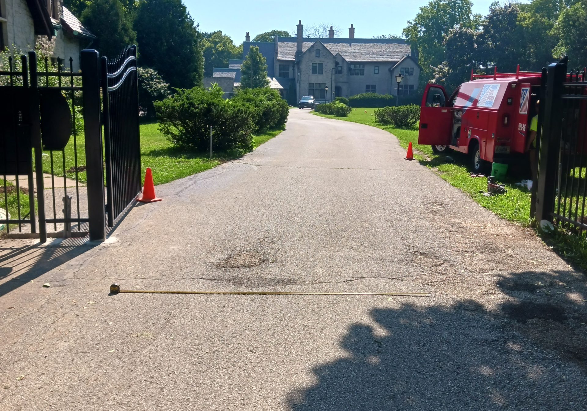 Driveway with black metal gate and red barrier gates on both sides.