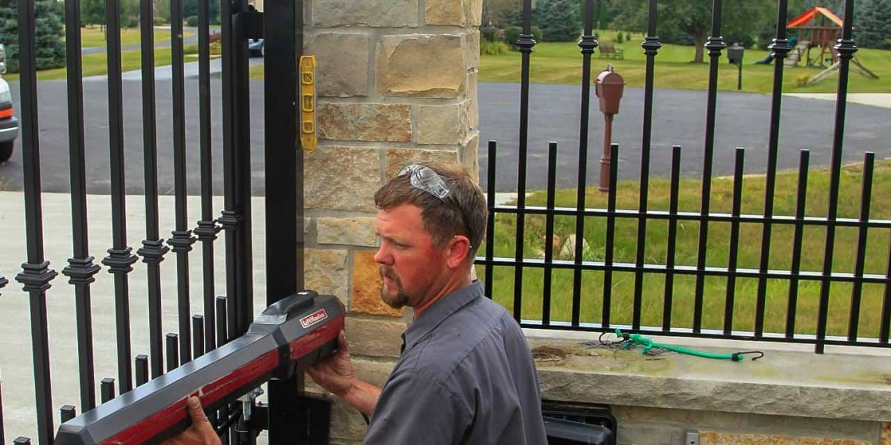 Technician installing a power gate opener at a residential property.
