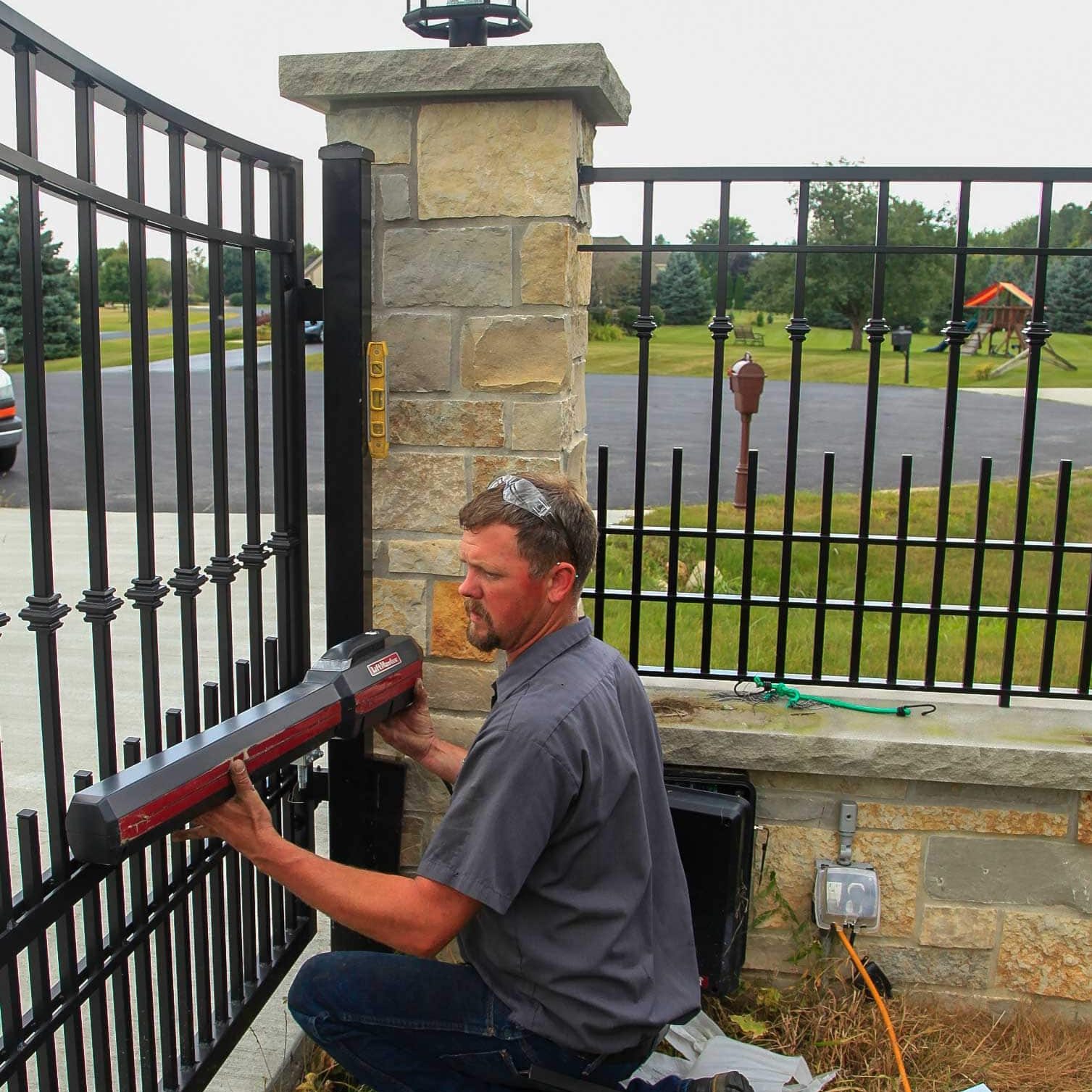 Technician installing a power gate opener at a residential property.